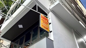 Un edificio con un cartel que indica 'HAPU APARTMENT by PHM', señalando la ubicación del apartamento.