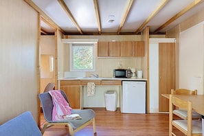 A compact kitchen with wooden cabinets, a microwave, a coffee maker, and a small refrigerator. - Lakeside 2BR Chalet for Four (Moncontour)