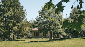 A house with a tiled roof, surrounded by a grassy lawn and trees.