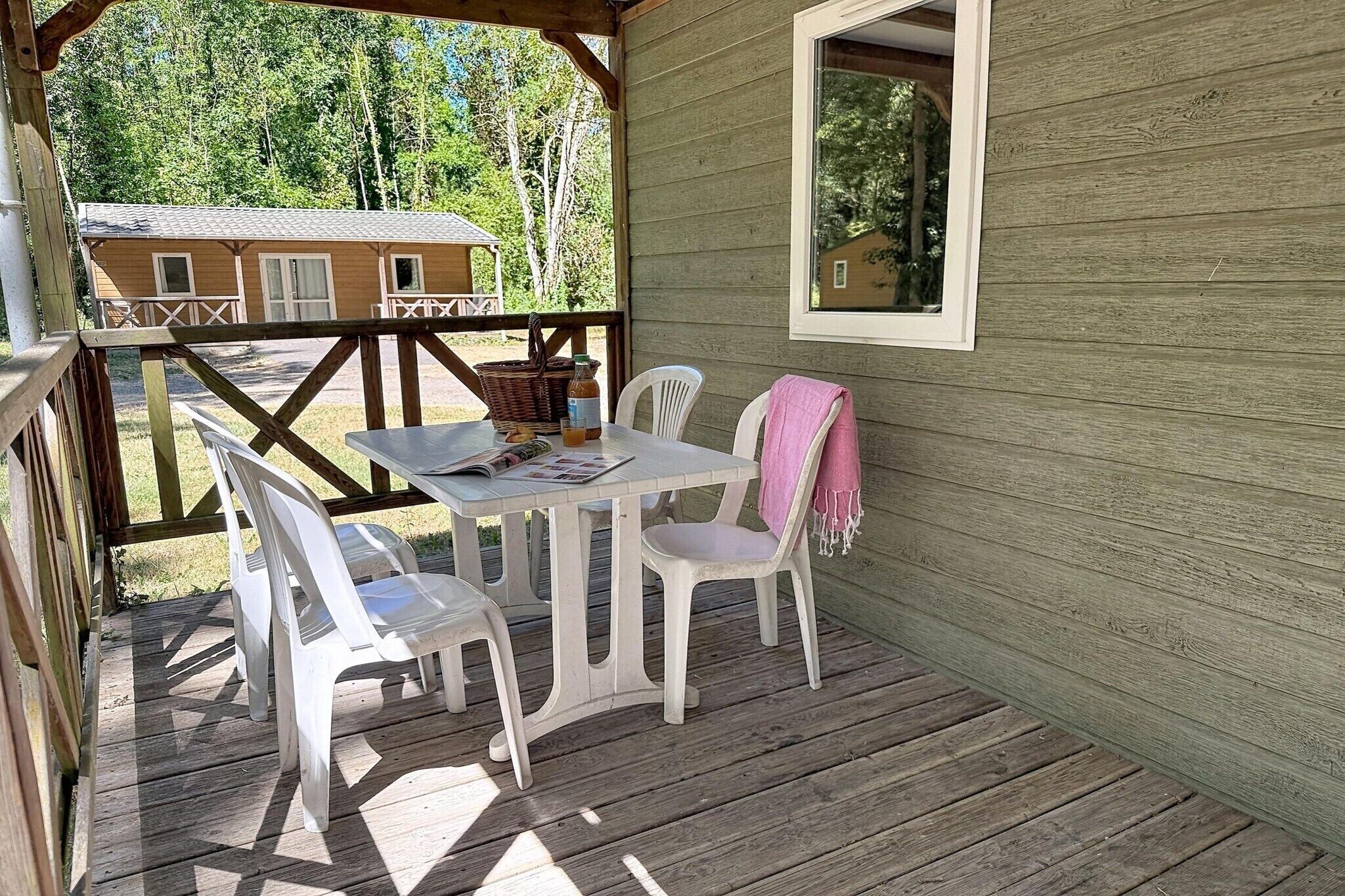 A wooden deck with a table and chairs, a window, and a view of a house in the background.