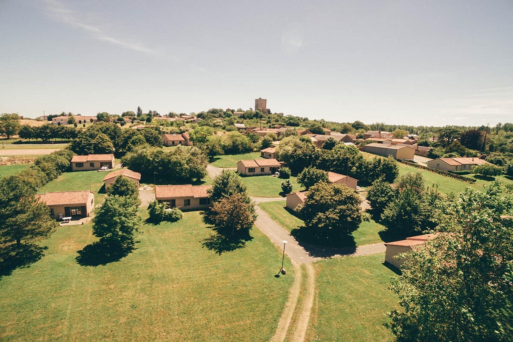 Et boligområde med flere huse, et centralt tårn og en velplejet græsplæne.
