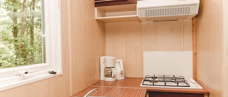 Una kitchenette compacta con estufa a gas, cafetera y pileta.