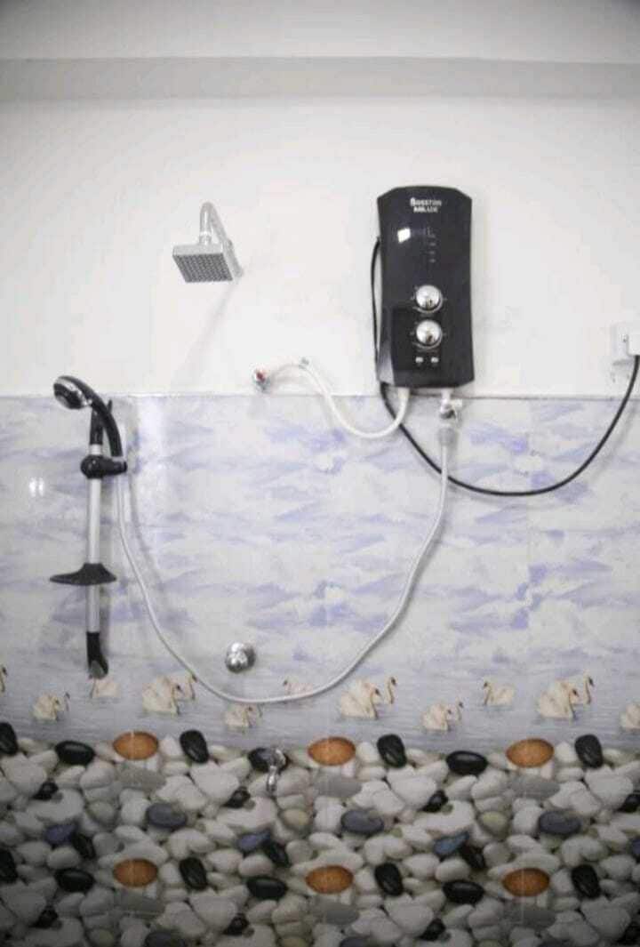 A shower with a handheld showerhead and a wall-mounted control panel.