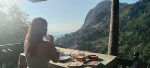 A person dining at a table with a view of a mountainous landscape. - Dream Nest Ella (Ella)