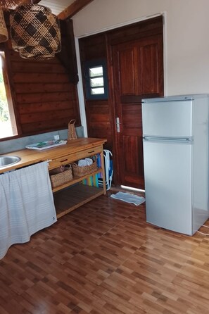 Eine Küche mit Holzboden, einem weißen Kühlschrank, einem Holztisch mit Spüle und einer Tür mit Fenster.