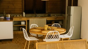 A cozy kitchen with a round wooden table, white chairs, and a built-in refrigerator. - "Ti Kaz Soleil" Creole House - Tropical Garden, Peace and Comfort in Sainte-Rose (Sainte-Rose)