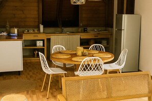 Eine gemütliche Küche mit einem runden Holztisch, weißen Stühlen und einem Einbaukühlschrank.