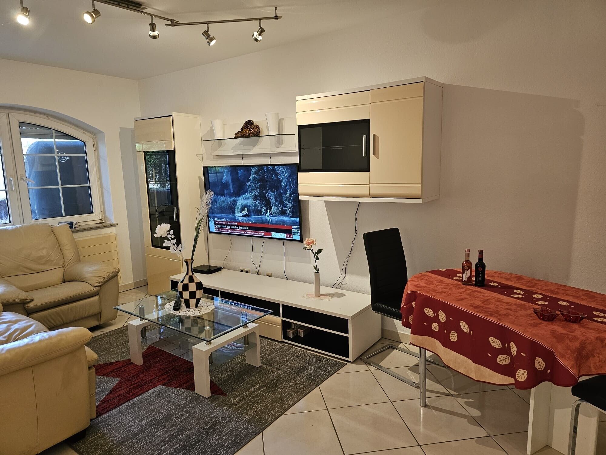 Un salon moderne comprenant un canapé, une table basse, un téléviseur et un coin repas avec une table et des chaises.