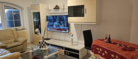 Un salon moderne comprenant un canapé, une table basse, un téléviseur et un coin repas avec une table et des chaises.