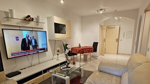 A modern living room with a flat-screen TV, a glass coffee table, and a beige sofa. - Nice small apartment for 2 in Kirkel with parking & quiet location (Kirkel)