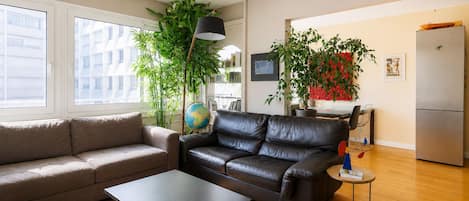 A modern living room with a sofa, coffee table, and a dining area with a table and chairs.