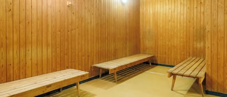 Un sauna con bancos de madera y un banco con respaldo.