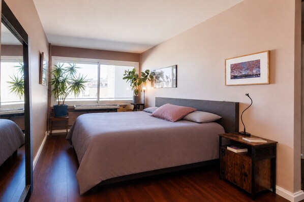 A bedroom with a bed, bedside table, lamp, potted plants, and a window. - Rooftop & Pool - Secure Parking (Paris)