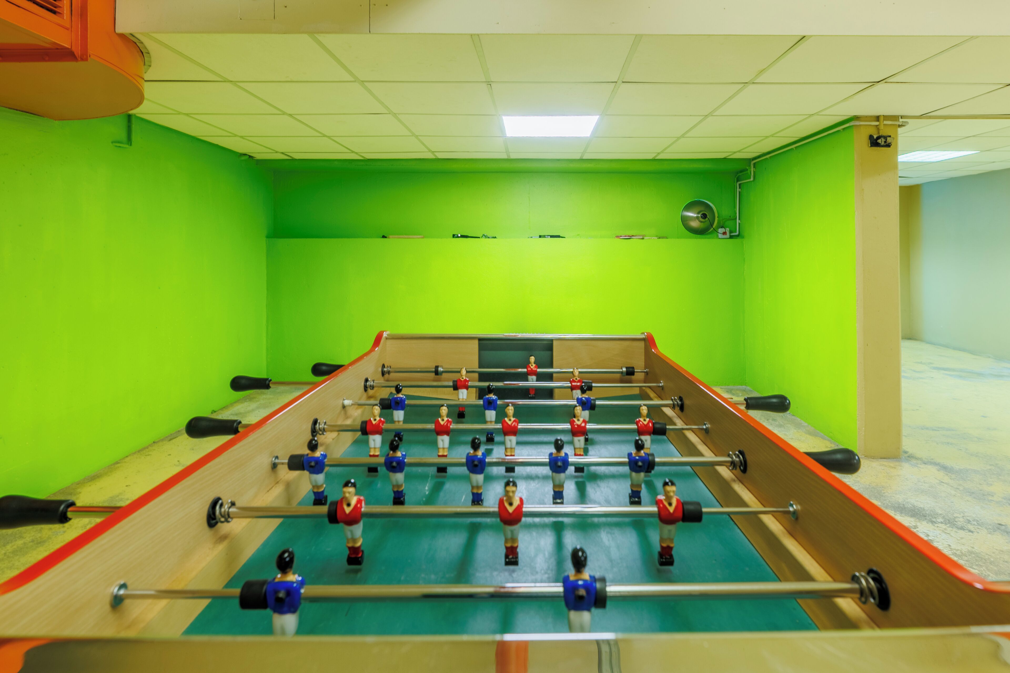 A foosball table in a room with green walls and a tiled ceiling.