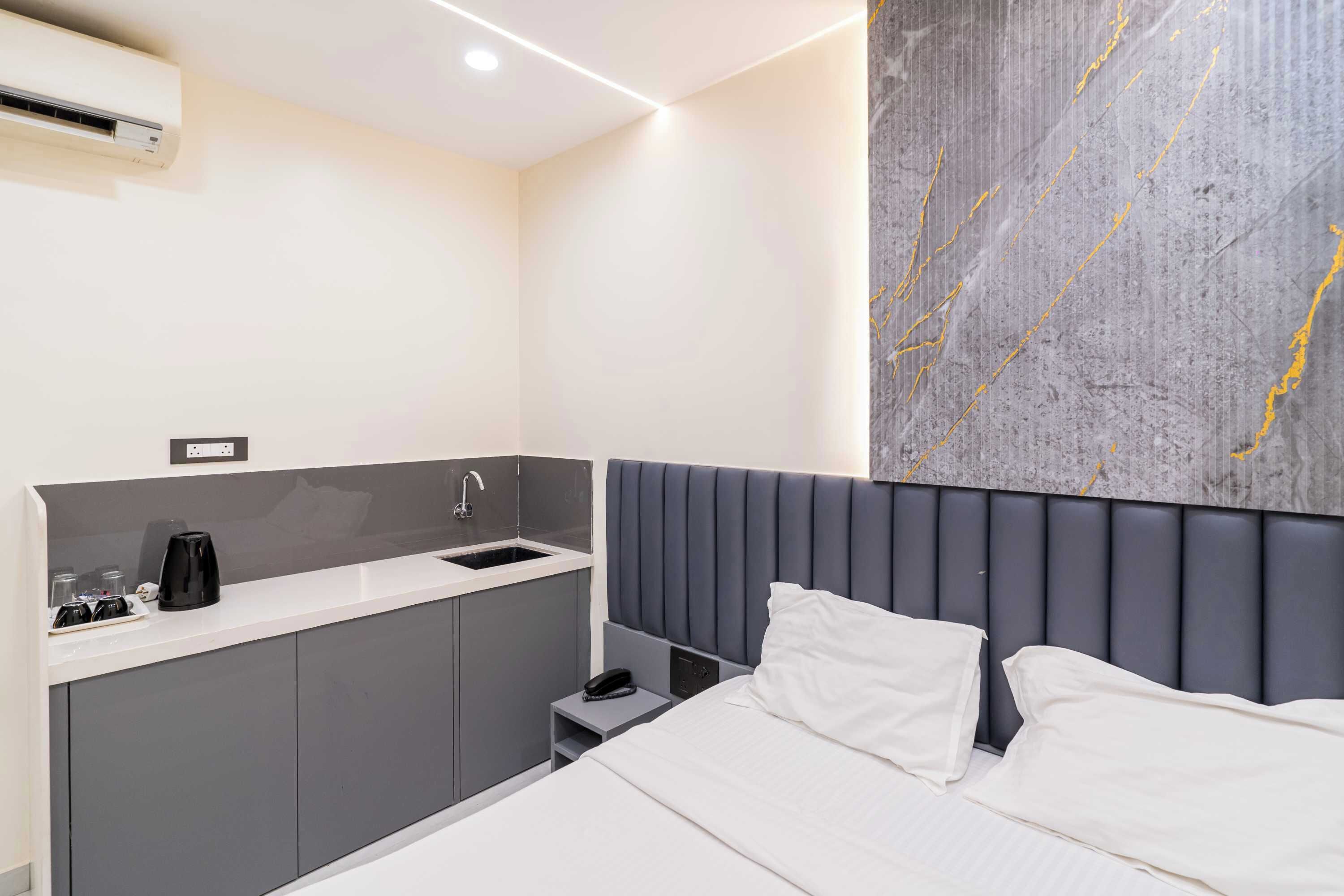 Una habitación de hotel moderna con una cama, una kitchenette pequeña y una pared decorativa de mármol.