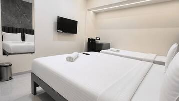 Een moderne hotelkamer met een groot bed, een flatscreen televisie, een plafondventilator en een wand bekled met marmer.