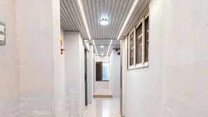 Un pasillo con piso brillante, paredes blancas y techo metálico.