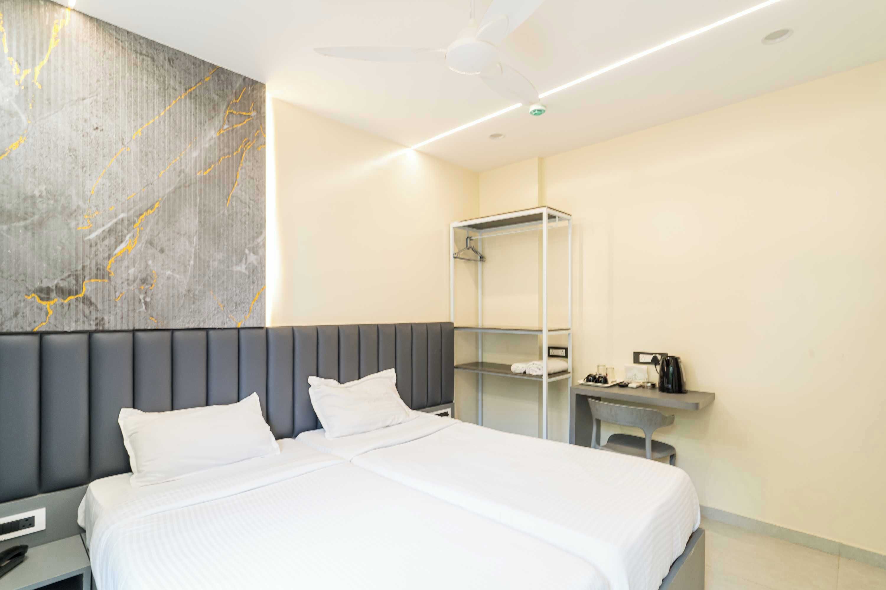 Ein modernes Hotelzimmer mit einem großen Bett, einem Nachttisch, einem Schreibtisch mit Kaffeemaschine und einem Kleiderschrank.