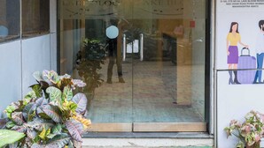 La entrada a Lake Bloom Residency, con puerta de vidrio, un letrero sobre la puerta y plantas en macetas afuera.