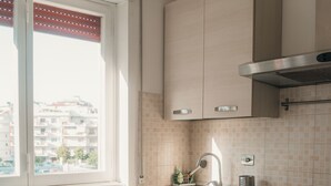 A kitchen with a window, a table, chairs, cabinets, a stove, and a tiled backsplash. - A cozy home for families and friends, just a stone's throw from the Vatican. (Roma)