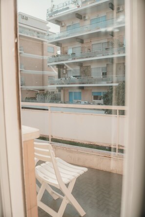 A balcony with a white chair, overlooking a multi-story building with balconies and air conditioning units. - A cozy home for families and friends, just a stone's throw from the Vatican. (Roma)