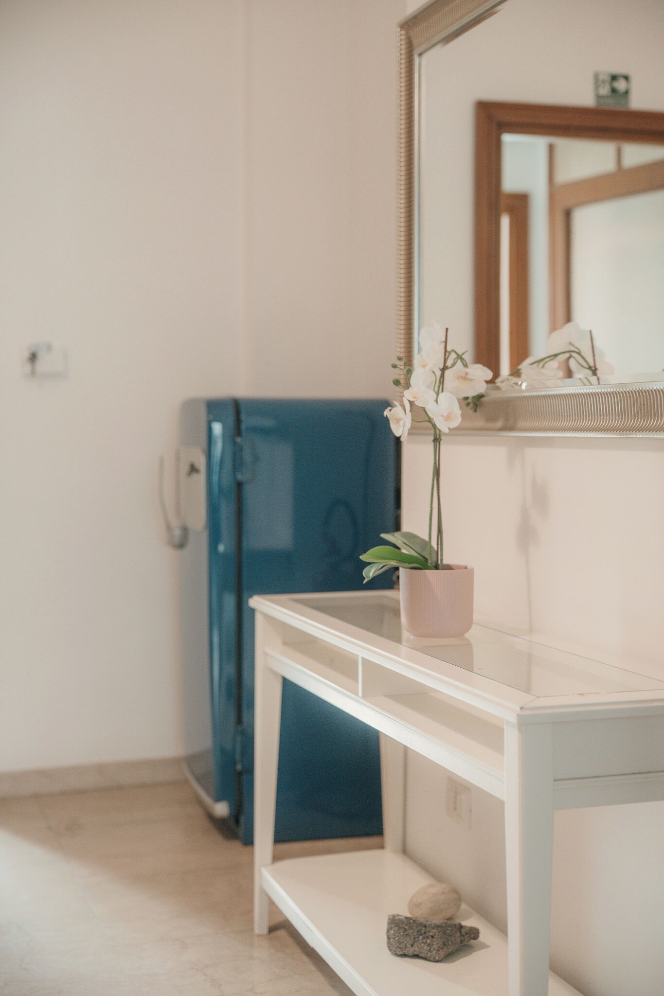 A bathroom with a white sink, a mirror, a blue towel, and a potted orchid.
