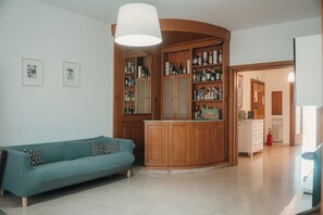 A living room with a teal sofa, a wooden cabinet with liquor bottles, and a white ceiling lamp. - A cozy home for families and friends, just a stone's throw from the Vatican. (Roma)