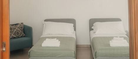 Quarto com duas camas de solteiro, luminária pendente e um quadro com a palavra 'Love'.