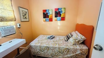 Une petite chambre à coucher comprenant un lit, un bureau et deux tableaux accrochés au mur.