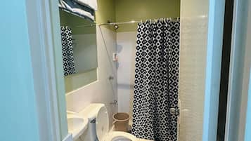 A bathroom with a toilet, a shower, and a sink.