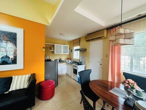A compact living space with a dining area, kitchenette, and a red trash bin. - Charming 3-bedroom House Rental in Guarded Cagayan de Oro Suburb (Cagayan de Oro)