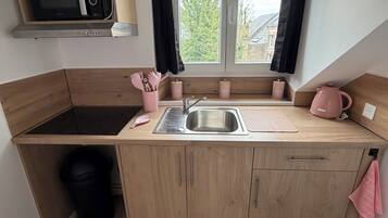 A compact kitchen with a microwave, sink, and wooden cabinets.