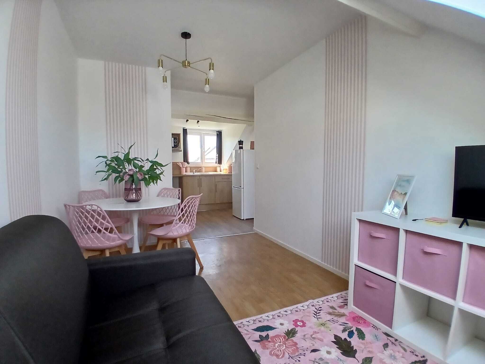 Un espacio habitable compacto con comedor, kitchenette y un mueble de televisión con cajones.