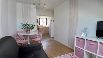 Un espacio habitable compacto con comedor, kitchenette y un mueble de televisión con cajones.