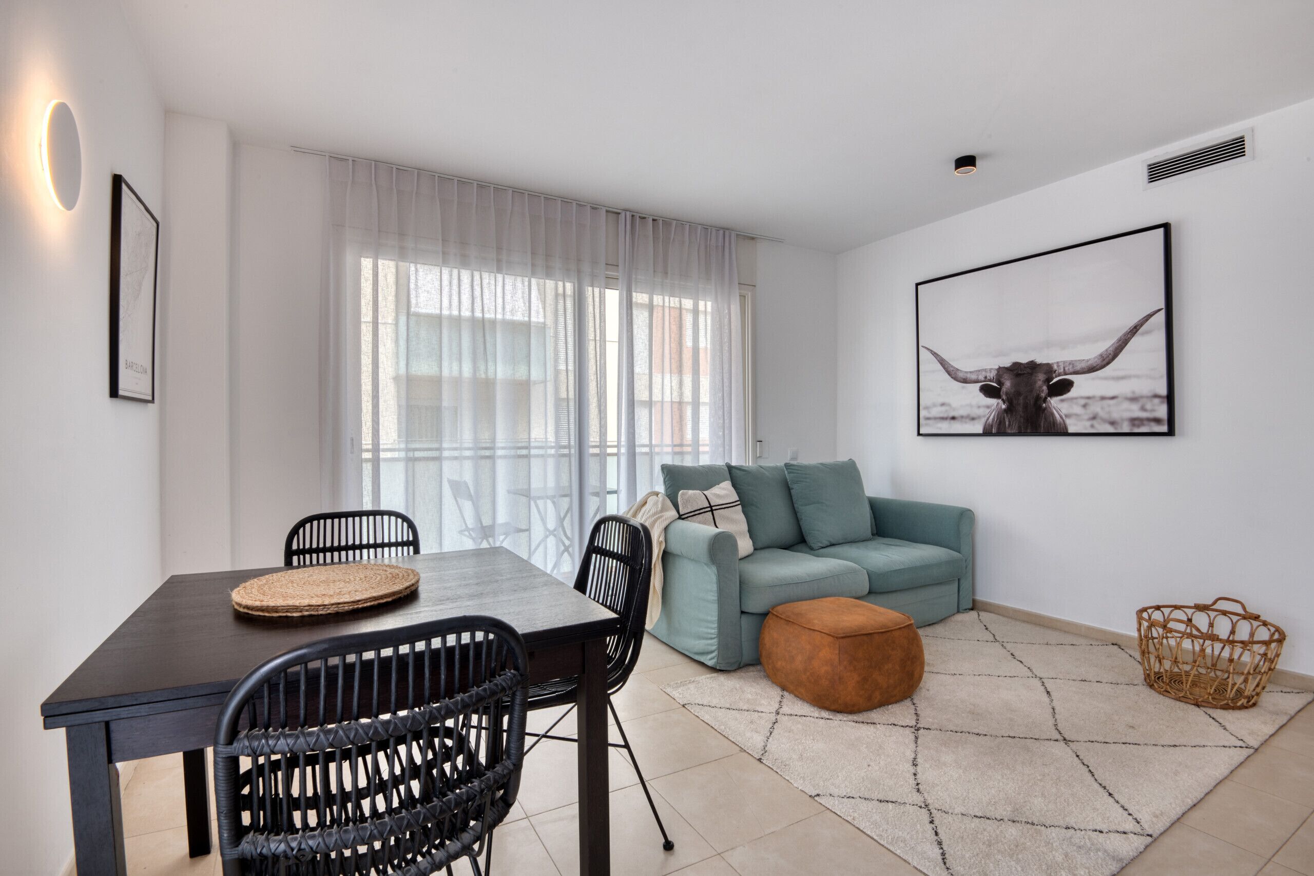 A modern living room with a dining table, chairs, a sofa, and a rug.
