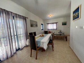 A dining area with a table set for four, surrounded by chairs, a sofa, and a small coffee table. - Jomavi Beach Eco-Villa (Polis Chrysochous)