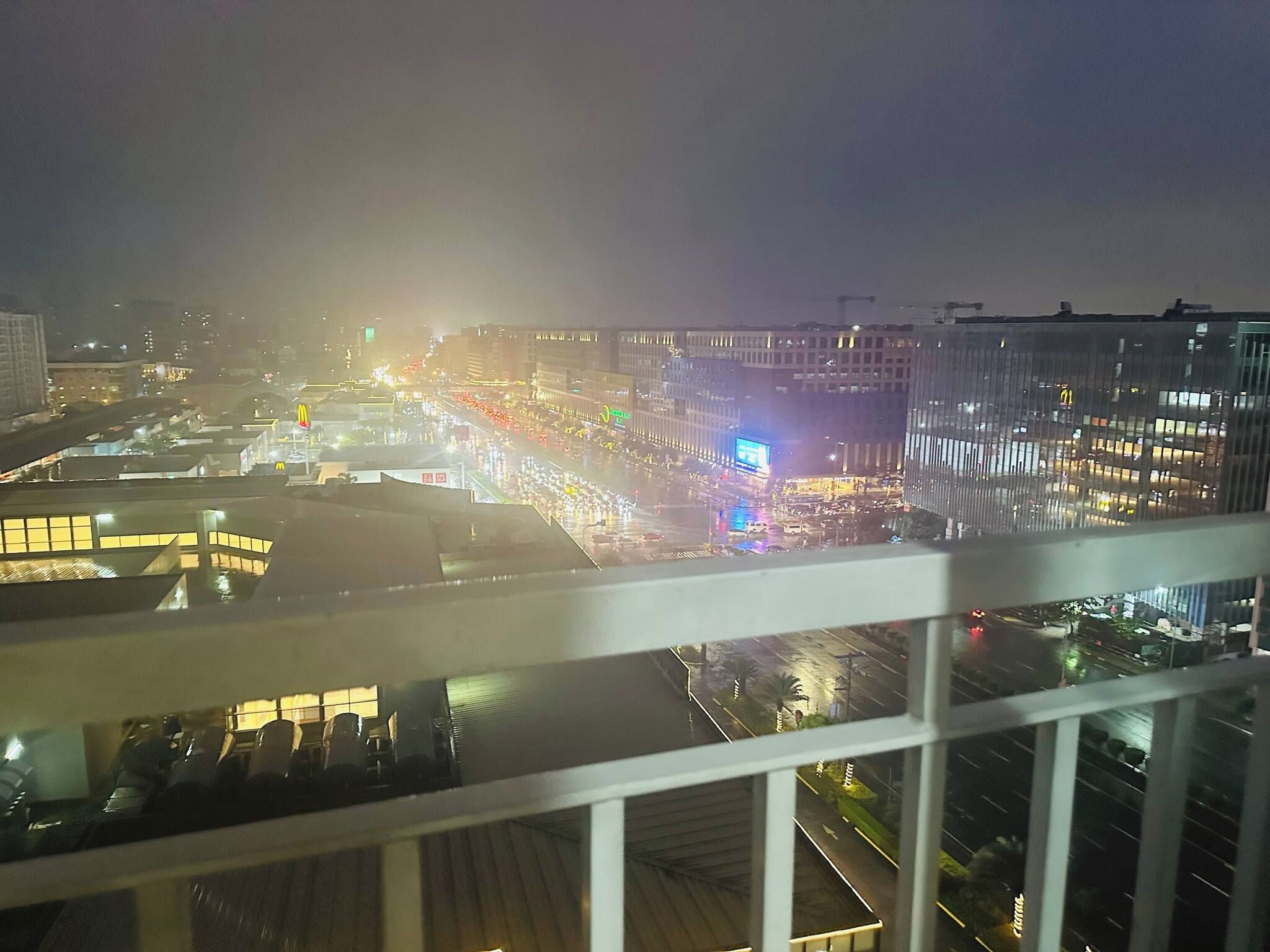 A nighttime cityscape with buildings, roads, and a McDonald's sign.