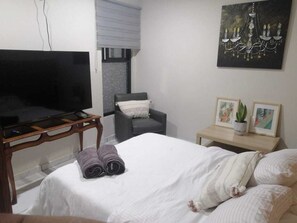 A hotel room with a bed, a television, a chair, a small table, and a wall with artwork. - The best location in the south—let us pamper you. (Ciudad de México)