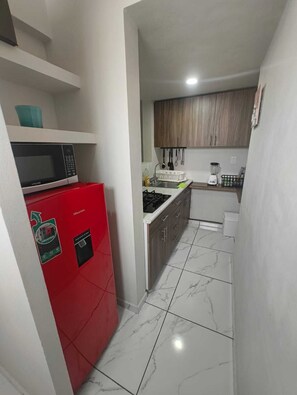 A compact kitchen with a red refrigerator, a microwave, a sink, and a stove. - The best location in the south—let us pamper you. (Ciudad de México)