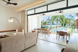 A modern hotel room with a large window, a pool, and a dining area. - 2-Bed Ocean View on Beach • Sol de Arena C5 (Las Terrenas)