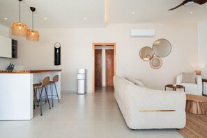 A modern living room with a sofa, a coffee table, and a dining area with chairs. - 2-Bed Ocean View on Beach • Sol de Arena C5 (Las Terrenas)