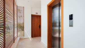 A hallway with a wooden door, a sliding glass door, and a wall-mounted sign. - 2-Bed Ocean View on Beach • Sol de Arena C5 (Las Terrenas)