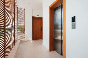 A hallway with a wooden door, a sliding glass door, and a wall-mounted sign. - 2-Bed Ocean View on Beach • Sol de Arena C5 (Las Terrenas)