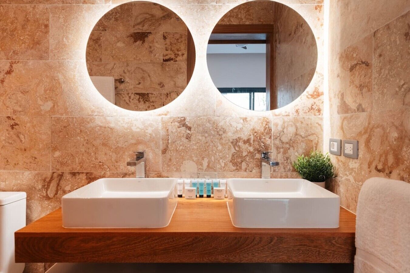 A bathroom with two sinks, a wooden countertop, and a mirror with a circular frame.