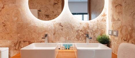 A bathroom with two sinks, a wooden countertop, and a mirror with a circular frame.