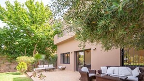 A patio area with outdoor furniture, a potted plant, and a building with a sliding glass door. - Riad Garden Targa Pool (Marrakech)