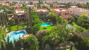 A residential area with multiple buildings, a swimming pool, and lush greenery. - Riad Garden Targa Pool (Marrakech)