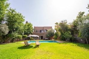 Ein modernes, zweistöckiges Haus mit Swimmingpool, umgeben von üppigem Grün.