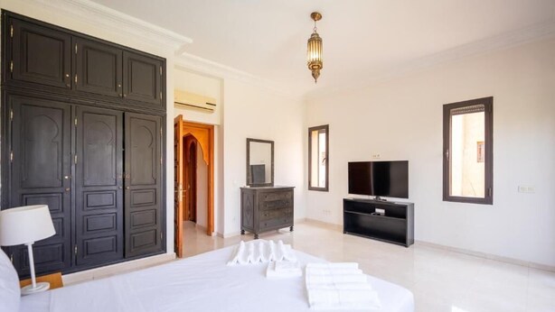A hotel room with a large bed, a dresser, a television, and a wardrobe. - Riad Garden Targa Pool (Marrakech)