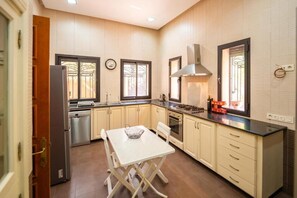 A kitchen with a dining table, cabinets, a stove, and a window. - Riad Garden Targa Pool (Marrakech)